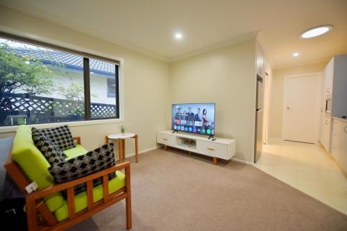 a living room with a couch and a tv at Family Friendly 1BR in Howick, Near Beach and Cafes in Auckland