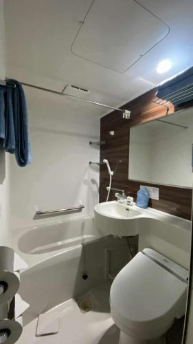 a white bathroom with a toilet and a sink at Nona Madarao in Madarao Kogen