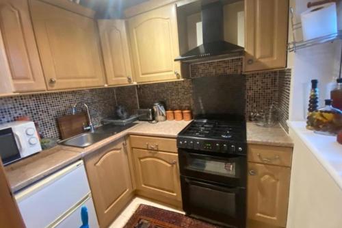 a kitchen with wooden cabinets and a stove top oven at Apartment - Sleeps 4 - Parking - Balcony - Garden in High Wycombe