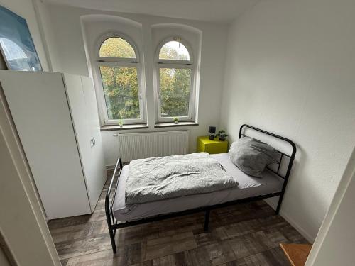 Un dormitorio pequeño con una cama y dos ventanas. en Sanierte Unterkunft in Glauchau Nähe zu VW Werk, en Glauchau