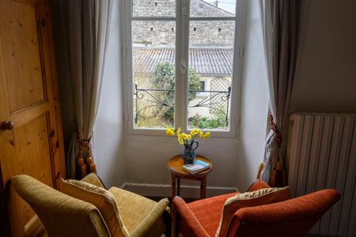 een kamer met twee stoelen, een tafel en een raam bij Les Jonquilles in Chef-Boutonne