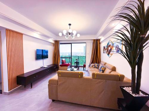 ein Wohnzimmer mit Sofa und Fernseher in der Unterkunft 3BD Apartment - Pool, Gym, Children Play Area in Nairobi