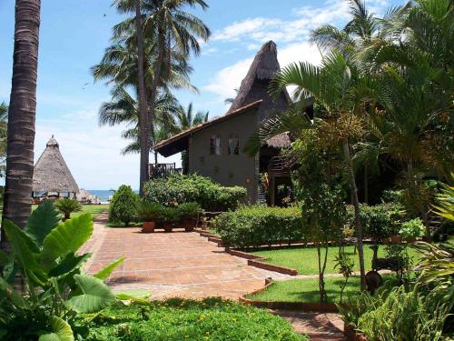 a house with palm trees and a brick walkway at Cabañas del Capitan in Rincon de Guayabitos