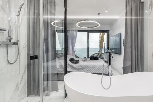 a bathroom with a bath tub and a bedroom at LUX - Bath with a Baltic View Rewal - SPA Access in Rewal