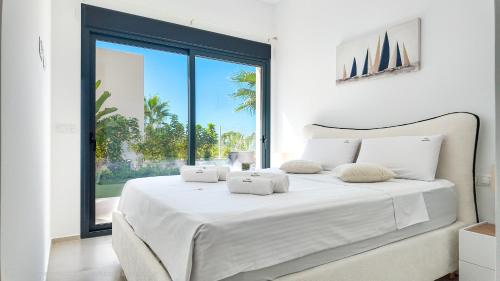 a white bedroom with a large white bed with a window at Family Villa Horizonte in Cala de Finestrat