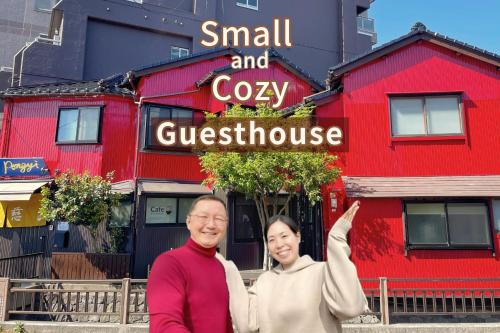 a man and woman standing in front of a red building at Kanazawa Guesthouse Pongyi in Kanazawa