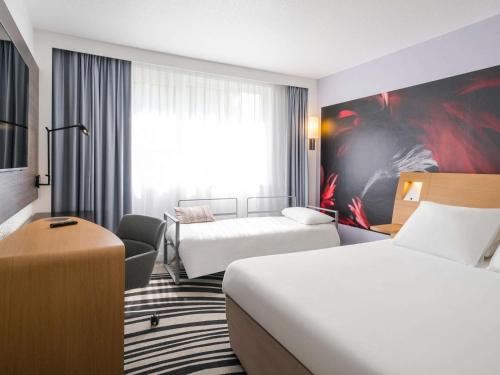 a hotel room with two beds and a couch at Novotel Saclay in Saclay