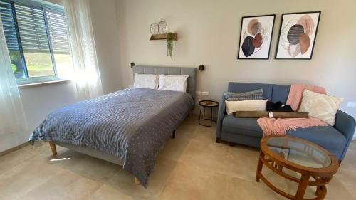 a bedroom with a bed and a blue couch at צימר על הנחל in Metsudat Menahem Ussishkin Alef