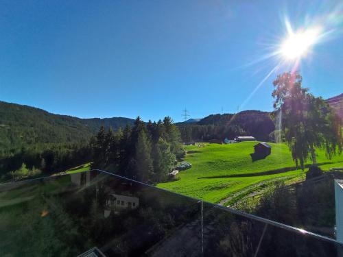 a view of a green field with the sun in the sky at Panorama Wildgrat in Wenns