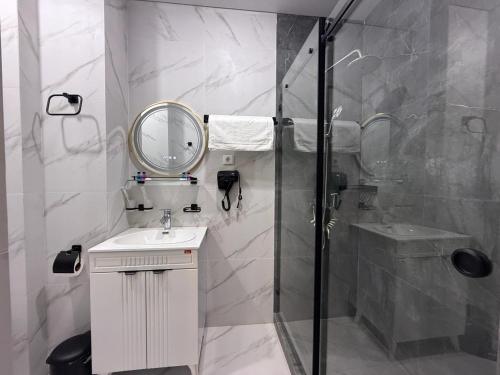 Un baño con ducha, lavabo y espejo. en Turkezm Hotel, en Urganch