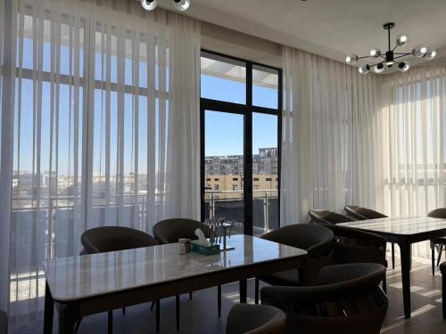 een eetkamer met tafels en stoelen en grote ramen bij Turkezm Hotel in Urganch