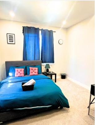 a bedroom with a bed with blue sheets and pink pillows at Flowealth Property Luxury Villa Near Lake Netflix TV Wifi in Calgary