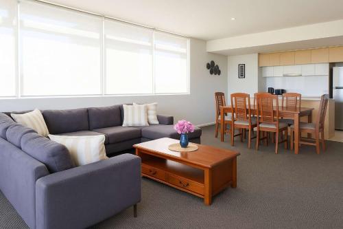 Home to Holiday at Central Islington Apartments Townsville في تاونزفيل: غرفة معيشة بها أريكة وطاولة