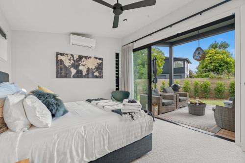 a bedroom with a bed and a sliding glass door at Boutique Coastal Retreat with Bath Walk to Beach in Mangawhai