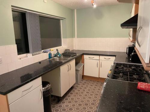 a kitchen with white cabinets and black counter tops at Family home near the beach in Saint Annes on the Sea