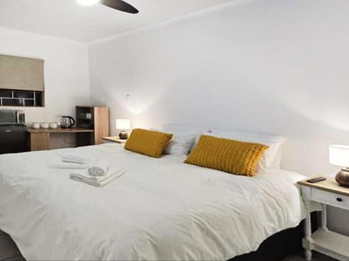 a bedroom with a white bed with two yellow pillows at In Vrede in George