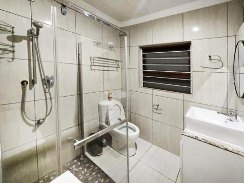a bathroom with a shower and a toilet and a sink at In Vrede in George