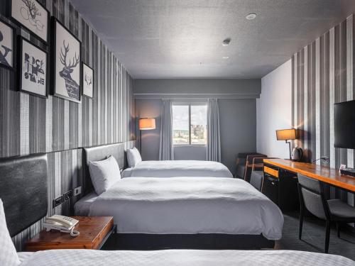 a hotel room with two beds and a desk at GUIDE HOTEL Kenting Resort in Hengchun South Gate