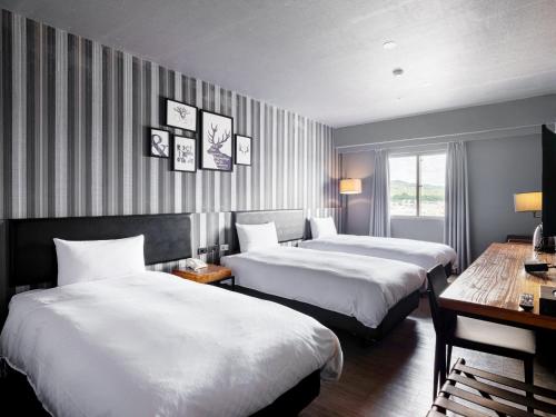 ein Hotelzimmer mit zwei Betten und einem Tisch in der Unterkunft Fulidun Hotel Kenting in Altstadt von Hengchun