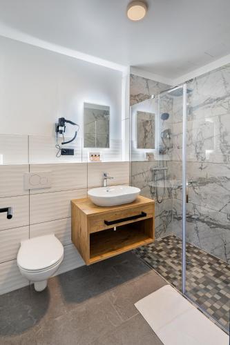a bathroom with a sink and a toilet and a shower at Rimedya Hotel - an der Messe München in Munich