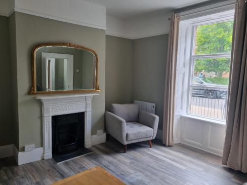 Una sala de estar con un espejo sobre una chimenea y una silla. en Moorefield Villa Newbridge, en Newbridge
