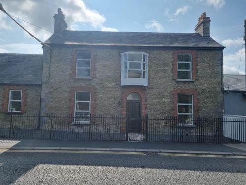a brick house with a fence in front of it at Moorefield Villa Newbridge in Newbridge