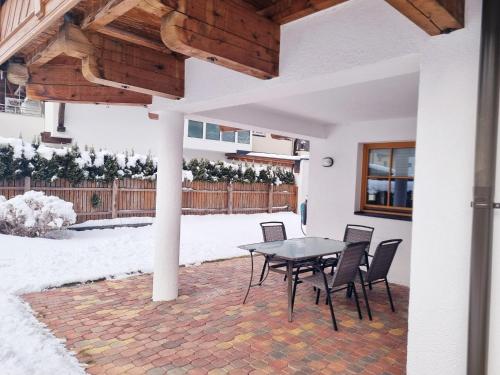 een patio met een tafel en stoelen in de sneeuw bij Apartment in Längenfeld near Ski Slopes in Längenfeld