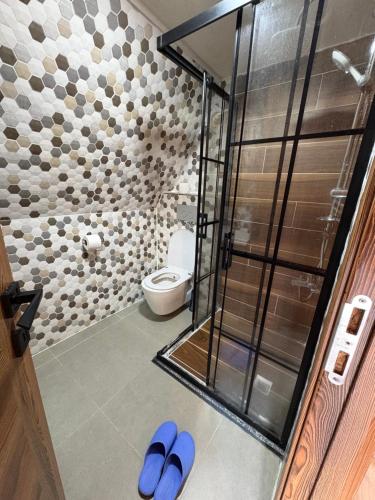 een badkamer met douche en toilet met blauwe slippers bij Paradise bungalov in Kocaeli