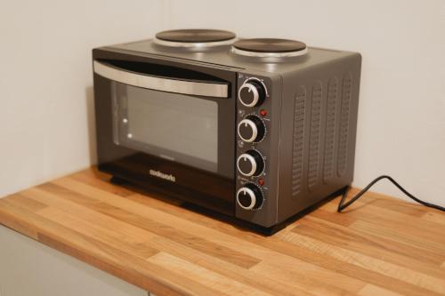 a black microwave sitting on a wooden table at Modern 2-Bed House Free Parking Contractors & Families Friendly Rotherham in Park Gate