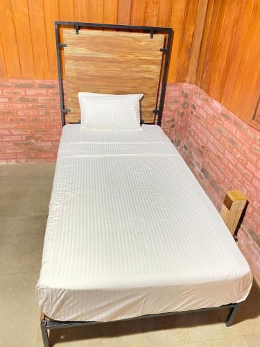 a white bed with a wooden headboard in a room at The Thinnai Farm in Jaffna