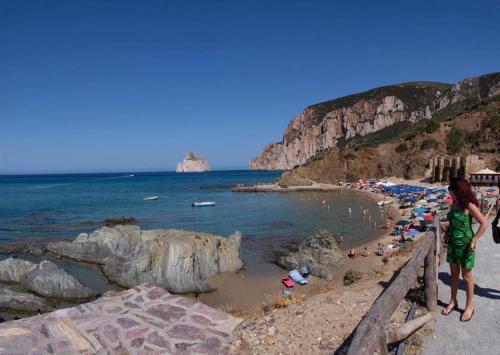 a group of people on a beach near the ocean at B&B Quintino Sella in Iglesias