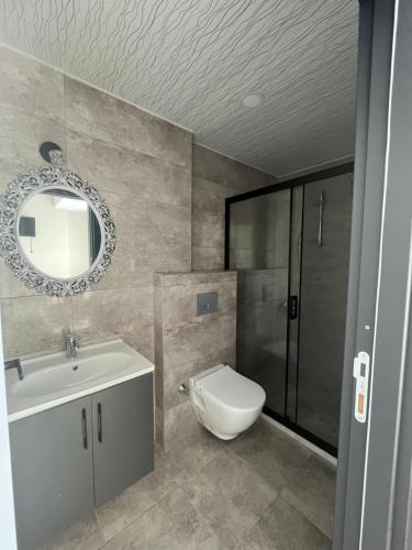 a bathroom with a toilet and a sink and a mirror at Mersin Panorama Otel in Kargipınarı