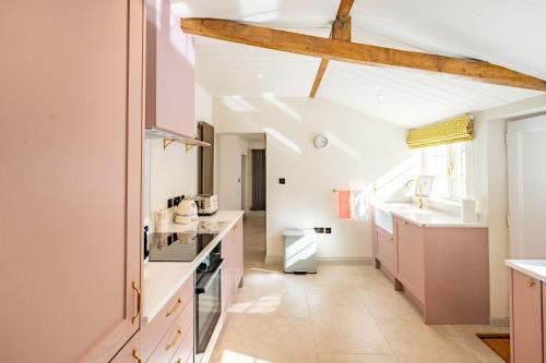 a kitchen with pink cabinets and a white ceiling at Waterhen Cottage in Docking