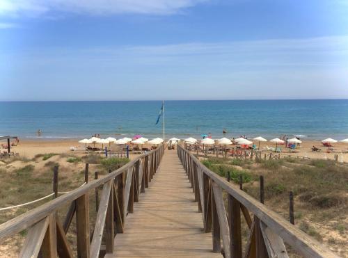 a wooden boardwalk leading to the beach with umbrellas at Villa Margarita, Guardamar Del Segura in Guardamar del Segura