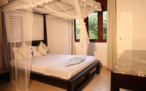 une chambre avec un lit à baldaquin et une fenêtre dans l'établissement Harris Villa, à Hikkaduwa