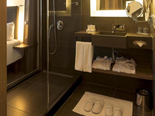 a bathroom with a sink and a shower and towels at Novotel Santos Gonzaga in Santos