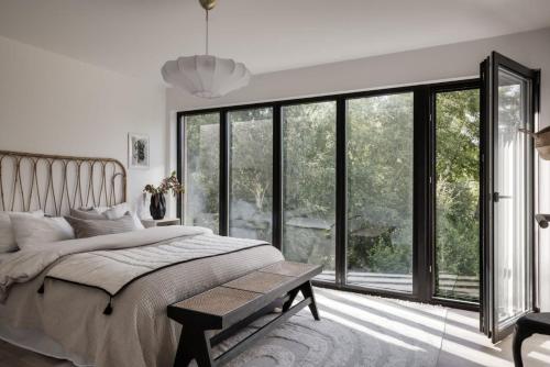 Newly built Scandinavian villa in Gothenburg في Hällsvik: غرفة نوم بسرير كبير ونوافذ كبيرة