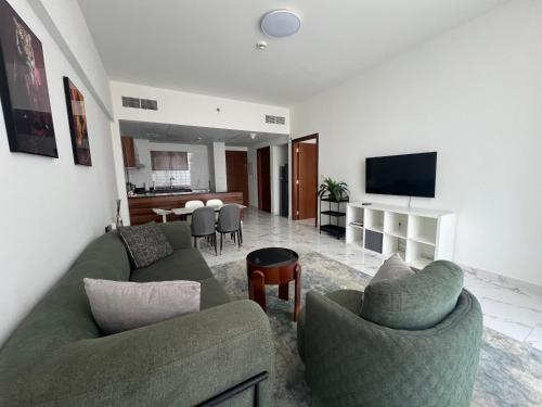 a living room with two green couches and a kitchen at Marina Al Hamra in Ras al Khaimah