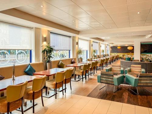 a restaurant with tables and chairs and a bar at Holiday Inn Express London Stratford by IHG in London