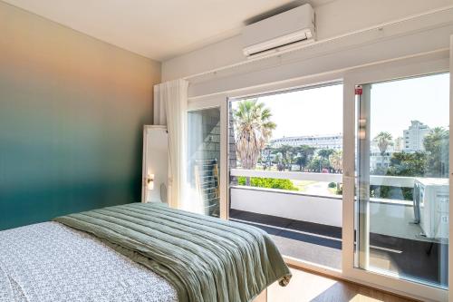 een slaapkamer met een bed en een groot raam bij Charming Estoril Apt One Min Walk to the Beach in Estoril