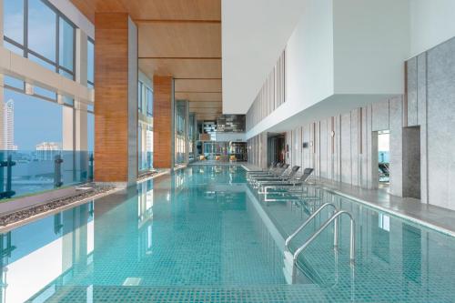 a large swimming pool with chairs in a building at Renaissance Bangkok Ratchaprasong Hotel in Bangkok