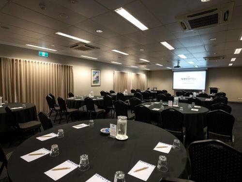 a conference room with tables and chairs and a screen at Novotel Darwin Airport in Darwin