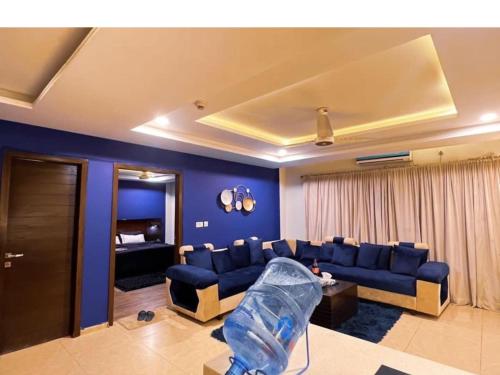 a living room with a blue couch and a bed at OSMA Living Full Furnished Apartment In Islamabad in Rawalpindi