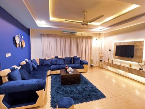a living room with a blue couch and a tv at OSMA Living Full Furnished Apartment In Islamabad in Rawalpindi
