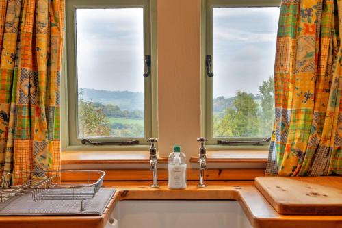 a kitchen with two windows and a sink with a detergent at Finest Retreats - Rough Close Farm Cottage in Ashover