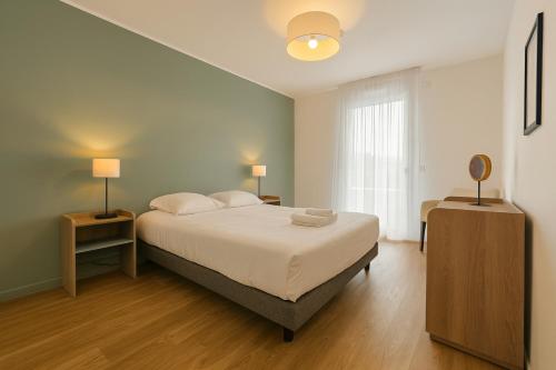una camera da letto con un letto, due lampade e una finestra di Zenao Appart'hôtels Le Raincy Thiers a Le Raincy