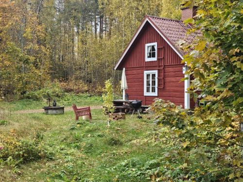 a red house with a grill and a bench in a yard at Romantic countryside SAUNA Cottage in Maakeski