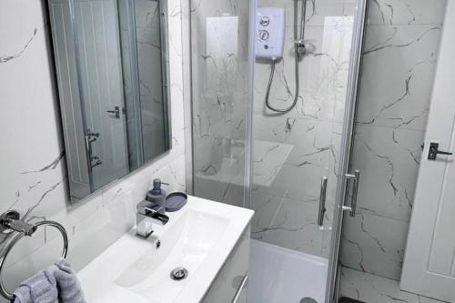 a bathroom with a sink and a shower with a mirror at 2 Bed apartment Sleeps 3 -Smart Tv -Private garden in Huddersfield