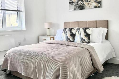 a white bedroom with a large bed and a window at 2 Bed apartment Sleeps 3 -Smart Tv -Private garden in Huddersfield