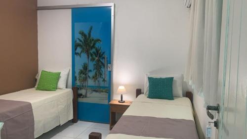 a bedroom with two beds and a mirror at Pousada Mar dos Sonhos in Paripueira